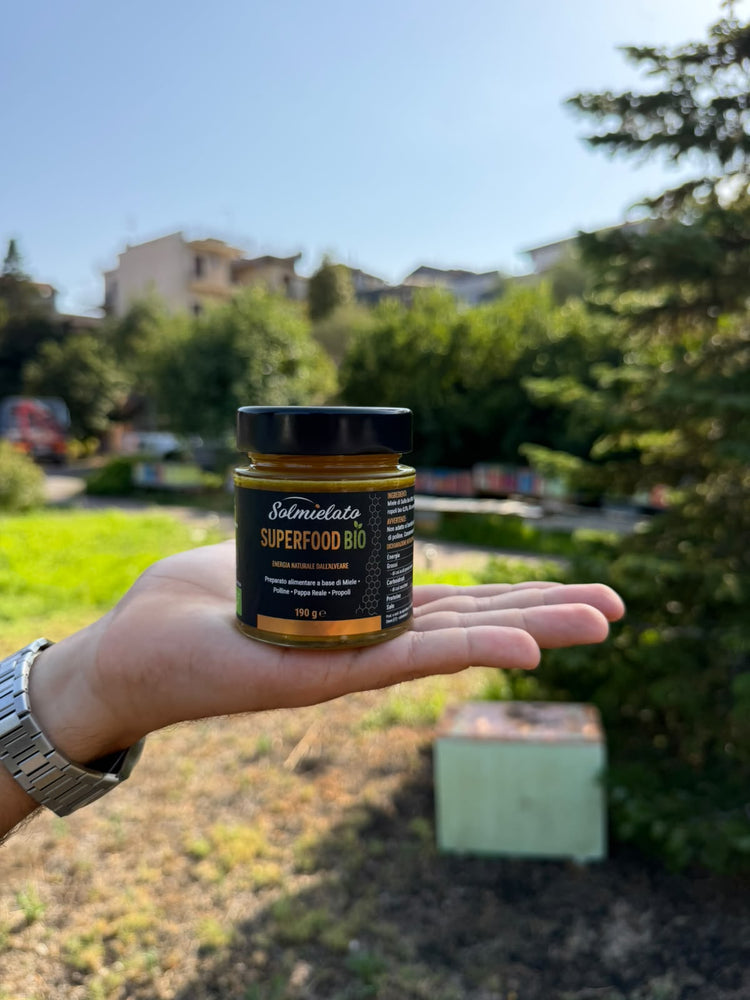 Superfood Bio Solmielato tenuto in mano davanti all'apiario